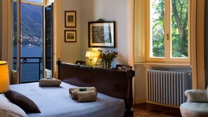 Ein Hotelzimmer mit Bett, Stuhl, Fenster und Blick aufs Meer sowie einer Heizung.