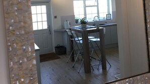 A kitchen with a dining area, a window, and a door. - Stunning Beachfront Apartment on Ferring beach (Ferring)