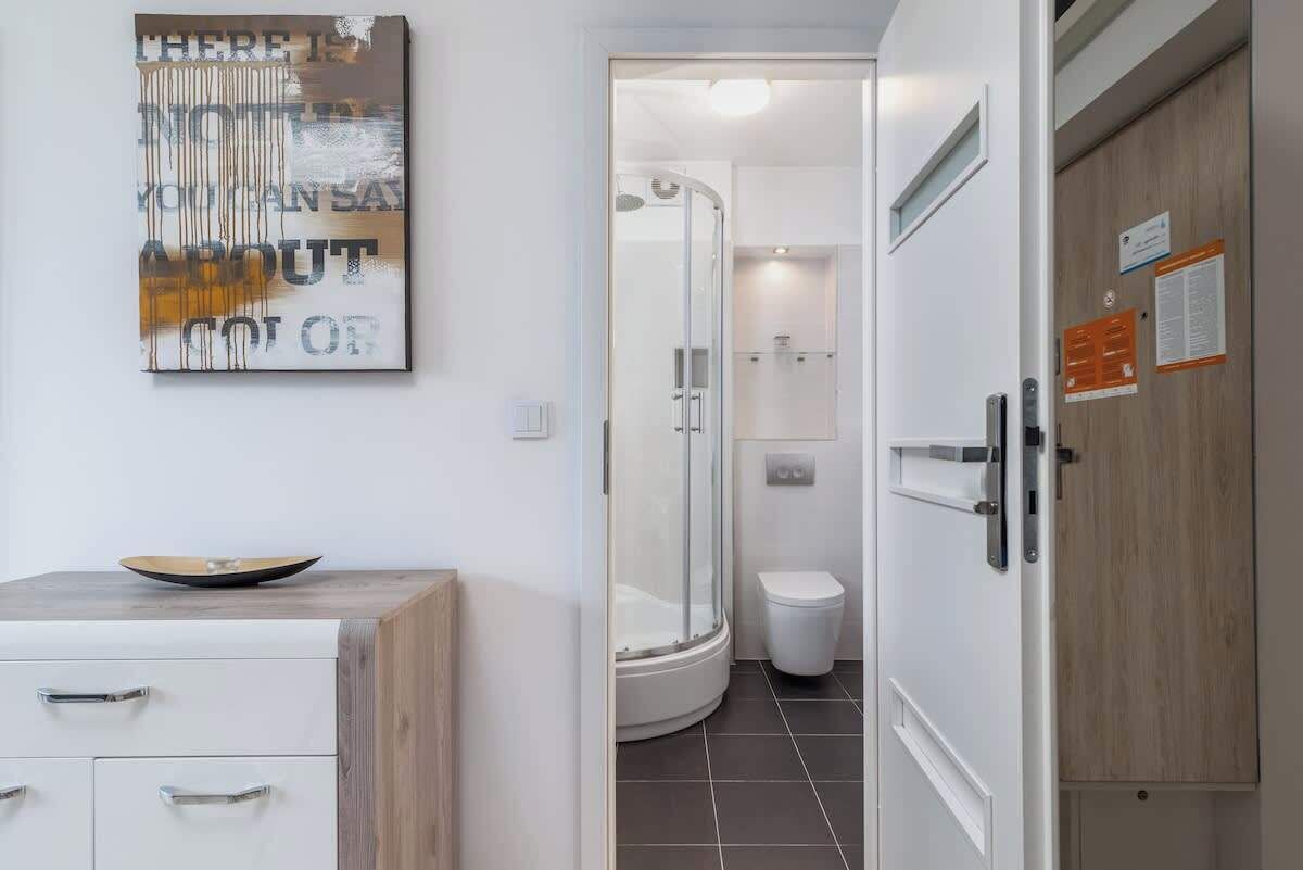 Ein modernes Badezimmer mit einer Duschkabine aus Glas, einer weißen Toilette und einem Schrank mit Schubladen.