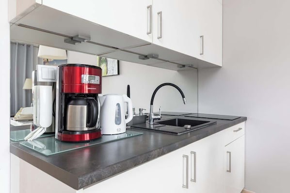 Eine moderne Küche mit Kaffeemaschine, Wasserkocher und Spüle.