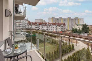 Ein Balkon mit Glastrennwand mit Blick auf ein Wohngebiet und Mehrfamilienhäuser.