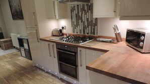 A modern kitchen with a central island, stainless steel appliances, and a tiled backsplash. - 4 Bedroom Farnborough Airport Accommodation (Hampshire)