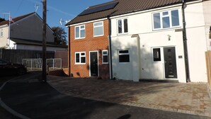 A two-story residential building with a brick facade, a tiled roof, and a paved driveway. - 4 Bedroom Farnborough Airport Accommodation (Hampshire)