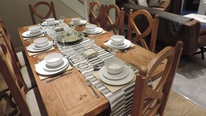 A dining area with a wooden table set for a meal, surrounded by wooden chairs. - 4 Bedroom Farnborough Airport Accommodation (Hampshire)