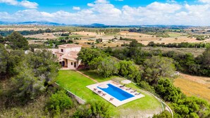 Eine Villa mit Swimmingpool, umgeben von üppiger Vegetation und Blick auf die Landschaft.