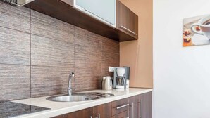 Una cocina moderna con un lavamanos de acero inoxidable, un protector contra salpicaduras de madera y una cafetera en la encimera.