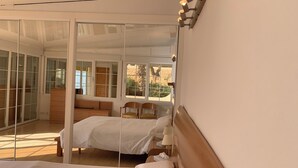 Une chambre à coucher comprenant un lit, une table de chevet, une lampe et une fenêtre donnant sur l’extérieur.