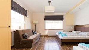 Ein Schlafzimmer mit einem Bett, einer Couch, einer Lampe und einem Fenster.