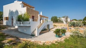 Una casa moderna con fachada blanca, sección de piedra y una escalera que conduce a la entrada.