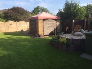 A backyard with a wooden shed, a fenced area, and a garden with plants and rocks.