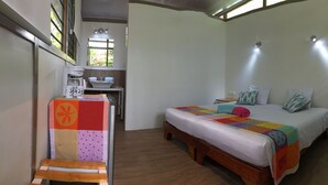 A bedroom with a bed, bedside table, and a small desk with a chair. - Pequeñito Paraíso by LEELOU (Jacó)