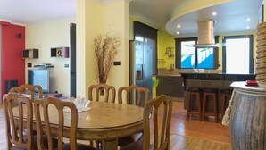 Une cuisine moderne avec un coin repas, comprenant une table ronde en bois, des tabourets de bar et une cuisinière intégrée.