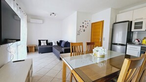 Una sala moderna con un sofá, una mesa de comedor y una zona de cocina con refrigerador y microondas.