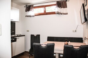 Une cuisine compacte avec un coin repas, une fenêtre avec des rideaux et un four encastré.