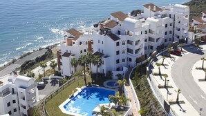 A white building with a swimming pool, located near a coastline. - 2 bedroom apartment front sea view (Torrox Costa)