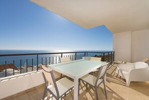 A balcony with a table and chairs, overlooking the sea. - 2 bedroom apartment front sea view (Torrox Costa)