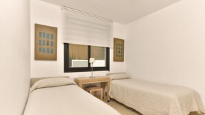 A bedroom with two beds, a desk, and a window with blinds. - 2 bedroom apartment front sea view (Torrox Costa)