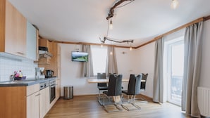 Una cocina moderna con armarios de madera, una zona de comedor con mesa y sillas, y un ventanal con cortinas.