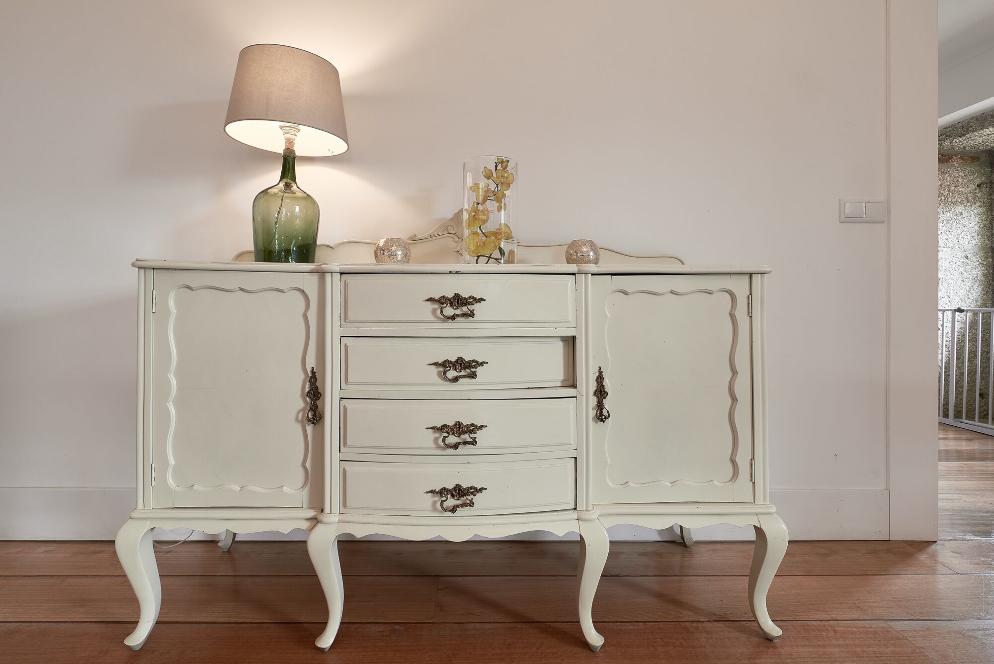 A white, antique-style dresser with three drawers and two doors, featuring ornate handles.