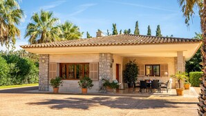 A two-story house with a tiled roof, stone walls, and a covered patio with outdoor furniture.