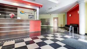 A reception area with a checkered floor, a reception desk, and a red wall. - Cozy Studio close to the Beach | Sauna and Gym (Kolobrzeg)