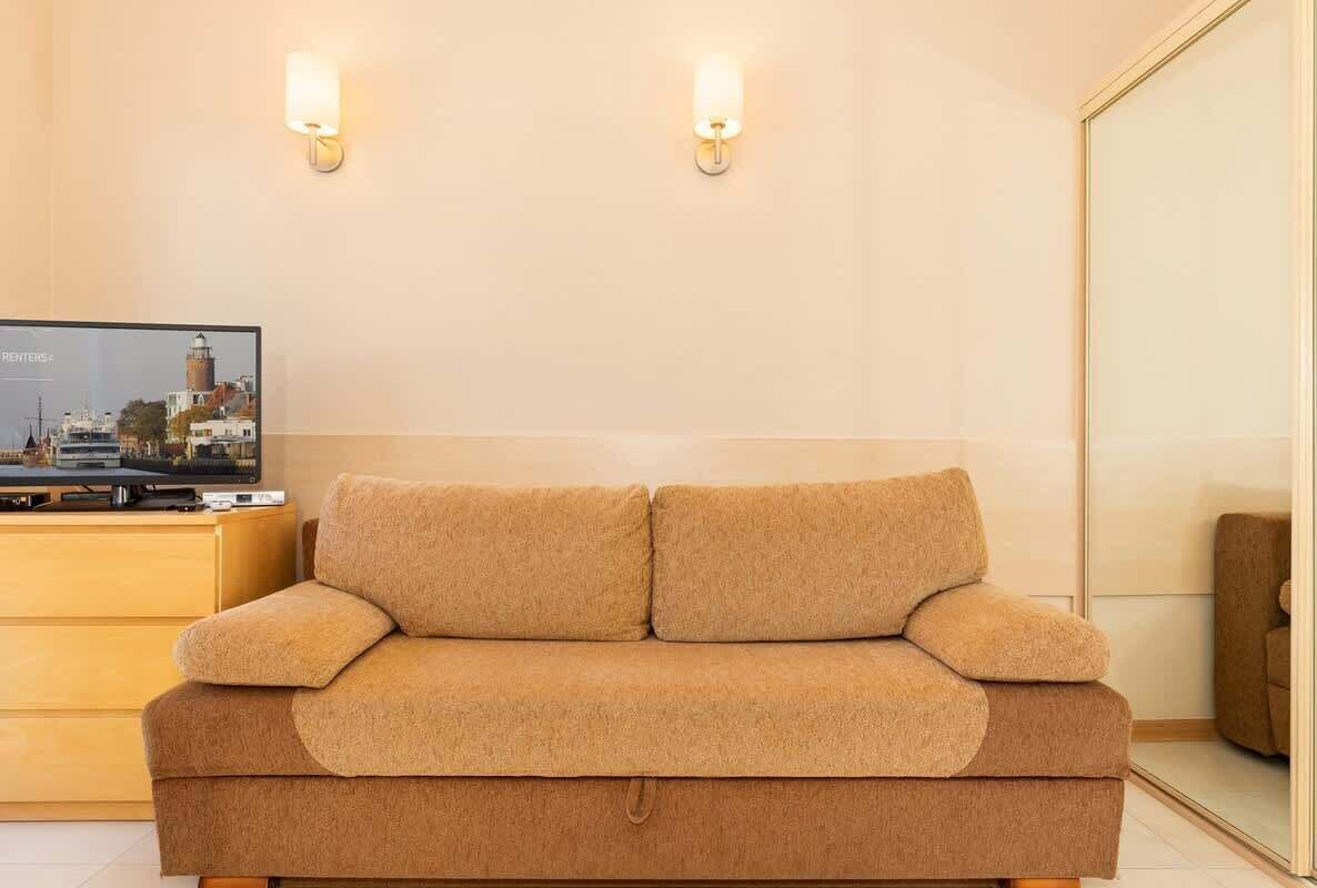 A beige sofa in a room with a television displaying a cityscape.