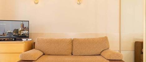 A beige sofa in a room with a television displaying a cityscape.