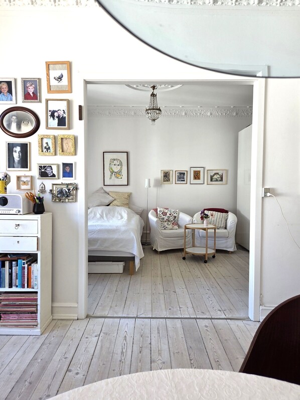 A bedroom with a bed, a chair, a small table, a bookshelf, and a wall with framed pictures. - City Apartment in Copenhagen with 1 bedrooms sleeps 4 (Copenhagen)