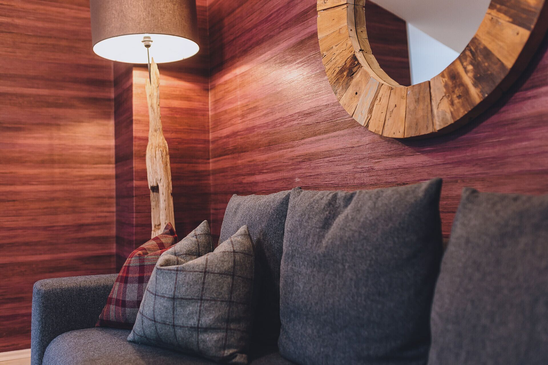 A wooden wall with a circular mirror and a lamp.