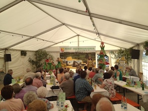 Guests can enjoy live performances and social gatherings under a spacious tent with tables and seating for all.