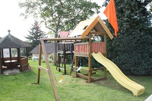 Children can play on the slide, swing, and in the enclosed playhouse in this backyard setting.
