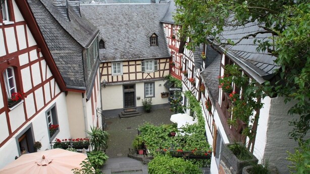A courtyard with traditional half-timbered buildings, a covered seating area, and a central staircase. - Haus Buchholz Apartment 2 multiple apartments available (Liesenich)