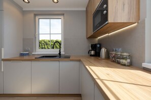 A modern kitchen with a window, built-in microwave, and wooden countertop. - Zastan | Zastan 302 | Spacious House | Garden with barbecue (Zastań)