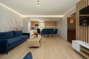 A modern living room with a sofa, a coffee table, and a dining area with chairs and a table.