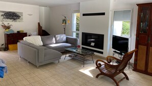 Ein Wohnzimmer mit grauem Sofa, Couchtisch, Holzstuhl, Flachbildfernseher und Kamin.