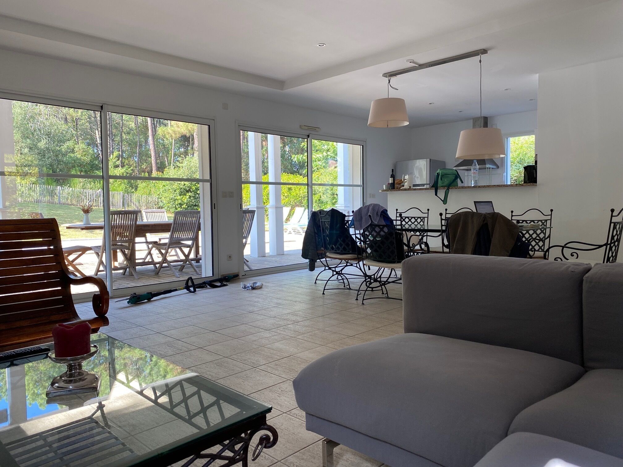 Un'ampia zona giorno con un'ampia porta vetrata che conduce a un patio, un divano grigio e un tavolino in vetro.