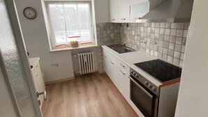 Eine kleine Küche mit Herd, Backofen und Fenster.