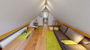 Ein gemütliches Dachzimmer mit Holzboden, einer Couch, einem kleinen Tisch und einer Heizung.