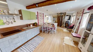 Eine moderne Küche mit Holzarbeitsplatte, ein Essbereich mit Tisch und Stühlen sowie eine Treppe zu einer oberen Ebene.