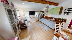 Eine moderne Küche mit Essbereich, Holzböden und einem eingebauten Fernseher.