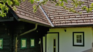 Ein traditionelles Haus mit Stein Fundament, dunkler Holzfassade und einem Ziegeldach.