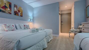 A bedroom with two beds, a nightstand, a dresser, and a door leading to another room.