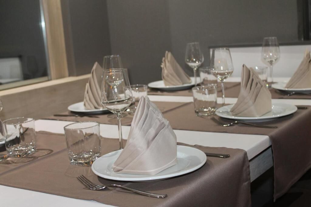 A dining table set with plates, napkins, cutlery, and glasses.