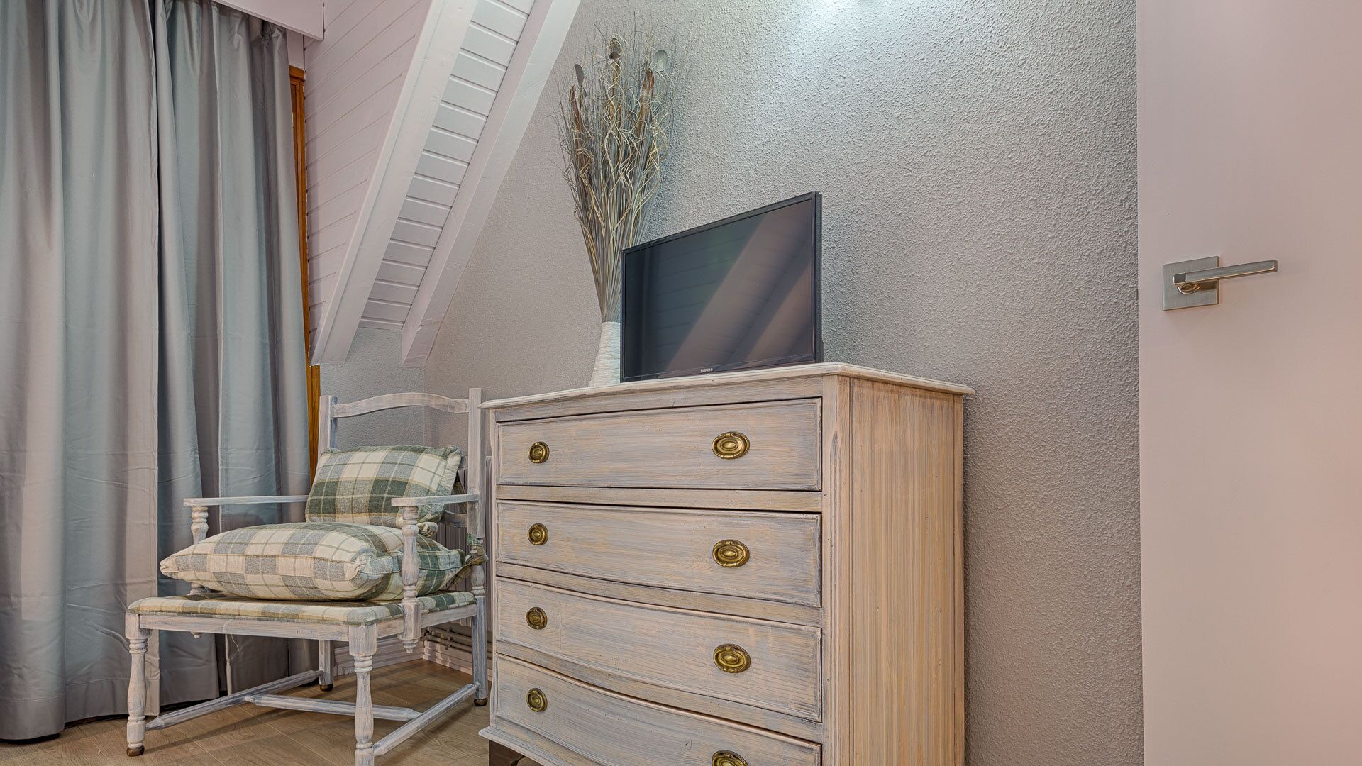 Un dormitorio con cama, cómoda, silla y ventana con vista al cielo.