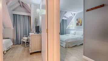 A bedroom with a bed, a bedside table, a chair, and a window with curtains.