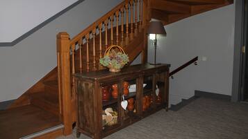Un escalier en bois, avec un panier de fleurs posé sur une console à côté.