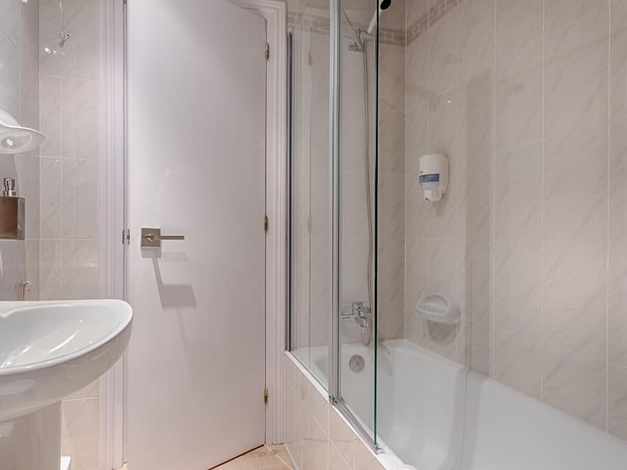 A modern bathroom with a glass-enclosed shower, a white sink, and a mirror.