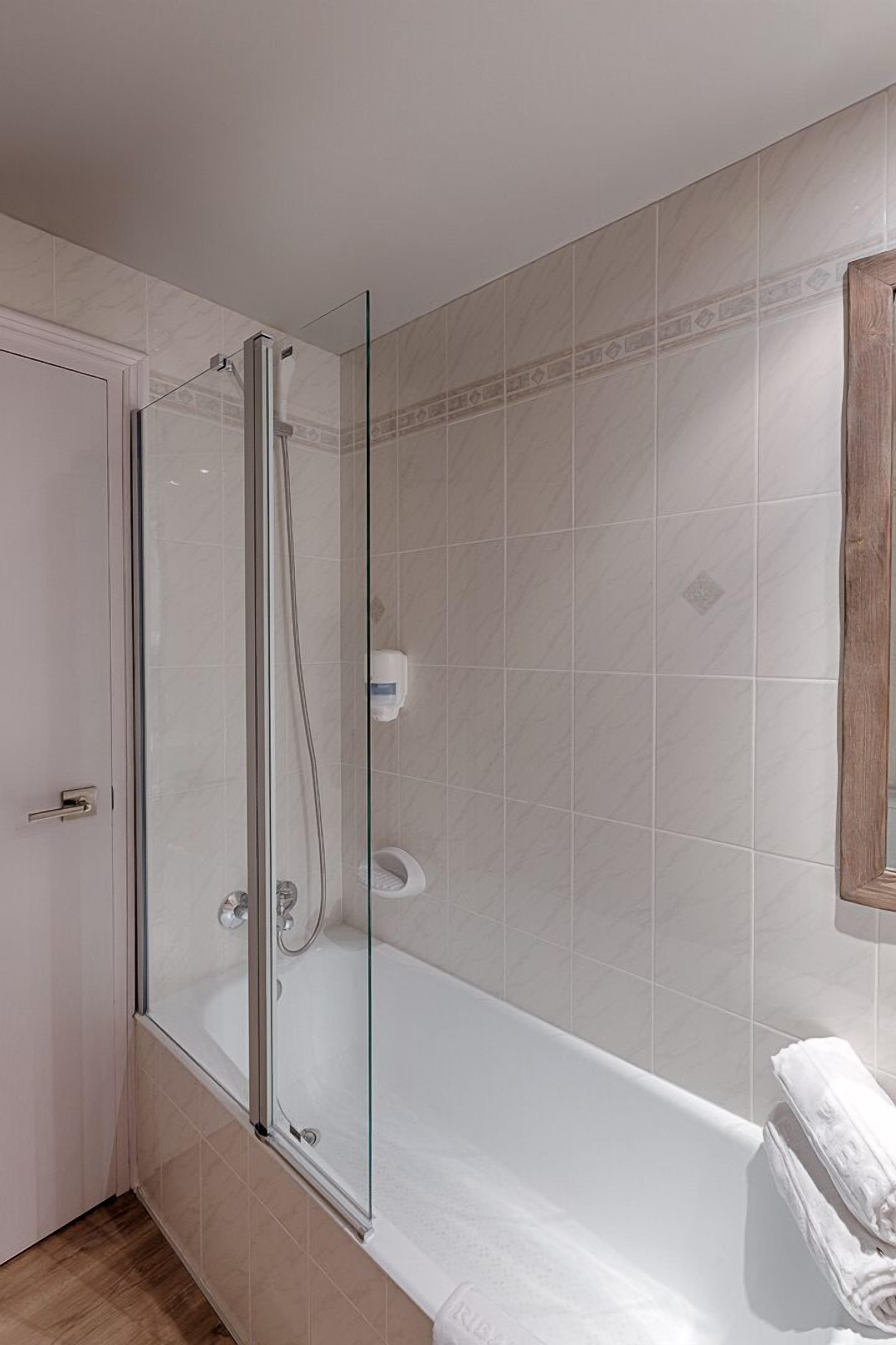 Et moderne badeværelse med en glasafskærmet bruseniche, et badekar og et toilet.