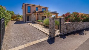 A two-story house with a stone facade, a balcony, and a gravel driveway. - Villa NATHALIE with private pool, jacuzzi and outdoor sauna (Linardici)