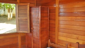 Una habitación de madera con una cama, una ventana y un armario de madera.